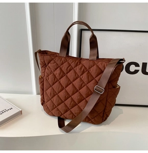 Dettaglio di una borsa a tracolla trapuntata marrone con texture, doppi manici e tasca