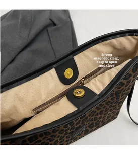 Detail view of leopard print bucket bag interior with dual magnetic gold buckles and zip pocket