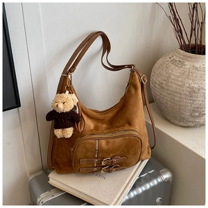 Dettaglio della borsa hobo in camoscio marrone con doppie fibbie e ciondolo a forma di orso