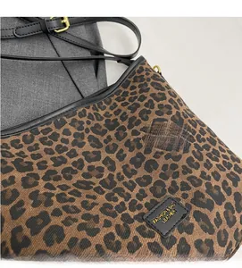 Detailed close-up of leopard print canvas bucket bag with black leather trim and logo tag