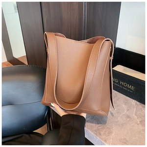 Close-up of brown lychee grain faux leather shoulder bag with wide strap and minimalist design