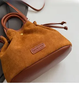 Close-up of caramel suede bucket bag showing drawstring closure and fashion text detail