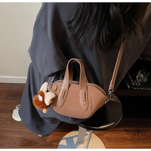 Vista dettagliata della mini borsa tote in pelle marrone con ciondolo e tracolla