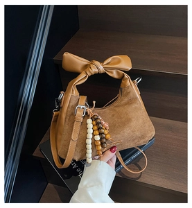 Détail d'un sac à main marron en daim rétro avec anse à nœud et perles en bois colorées