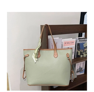 Detail of light green tote bag featuring lychee texture and brown contrast handles