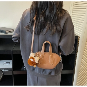 Dettaglio mini borsa a secchiello marrone in finta pelle con ciondolo a mostro