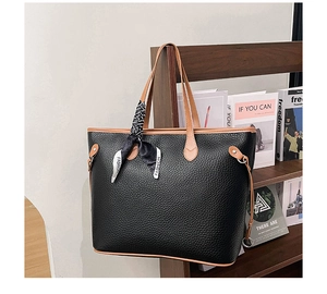 Detail of black pebbled leather tote bag with brown handles and fashion silk scarf accessory