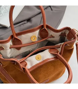 Detailed close-up of brown suede bucket bag featuring magnetic closure and interior lining