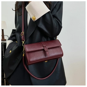 Dettaglio di una borsa retrò bordeaux in pelle con finiture dorate e manico superiore