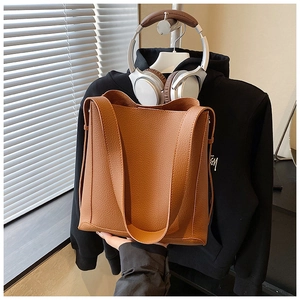 Close-up of deep brown lychee texture leather bucket bag with wide shoulder strap