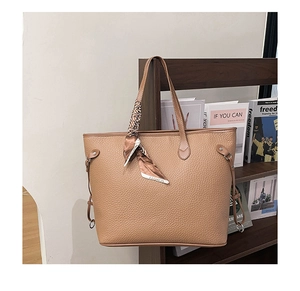 Close-up of brown litchi pattern leather tote bag with silk scarf and gold buckles