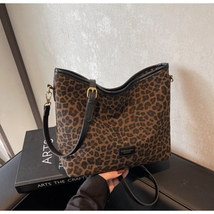 Detail view of leopard print bucket bag with gold hardware and black leather straps