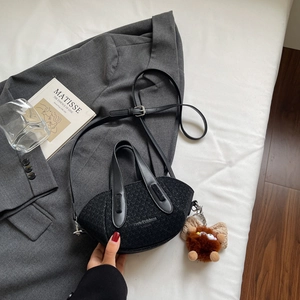 Dettaglio borsa a secchiello nera intrecciata con tracolla in pelle e ciondolo peluche