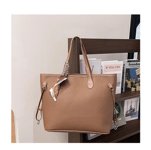 Detailed close-up of brown litchi-grain leather tote bag with elegant silk scarf detail