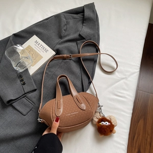 Dettaglio mini borsa a secchiello in pelle marrone con tracolla e ciondolo di peluche