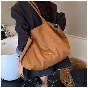 Close-up of caramel suede tote bag with signature label and blue checkered lining detail