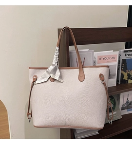 Detail of lychee pattern leather tote bag with brown handles and a stylish silk scarf