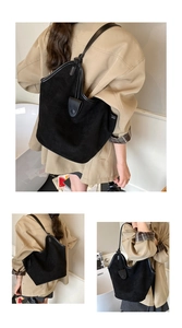 Detail of a black suede tote bag with leather trim and shoulder strap in a soft interior