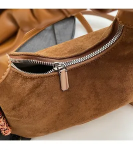 Détail macro de la fermeture éclair dorée lisse sur le sac en daim marron élégant