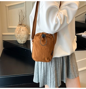 Detail of the brown drawstring crossbody bag with adjustable strap on a model