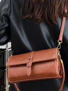 Borsa a tracolla retrò in pelle marrone con hardware dorato indossata da una modella