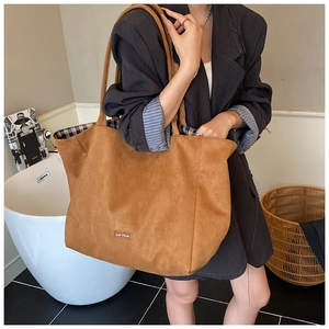 Close-up of brown suede tote bag with blue checkered lining and branding tag