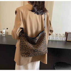 Detailed close-up of leopard print bucket bag with black leather trim and logo plaque
