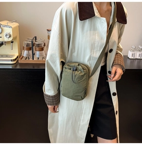 Detail view of olive green nylon crossbody bag with drawstring closure in a cafe setting