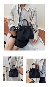 Detail view of black faux suede bucket bag with drawstring closure and metal logo