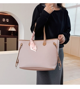 Detail of pink lychee leather tote bag with brown straps and silk scarf on the handle