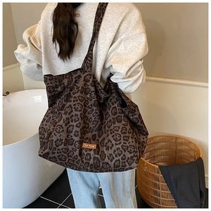 Detail of leopard print canvas tote bag featuring leather round patch and wide shoulder strap