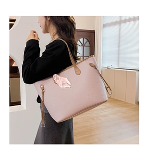 Close-up of pink litchi grain leather tote bag featuring a silk scarf and metal buckle detail