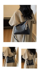 Detail of black pebbled leather crescent bag with adjustable strap and beaded charm
