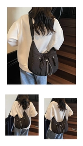 Close-up of black nylon crescent crossbody bag with white drawstrings and woven zipper pulls
