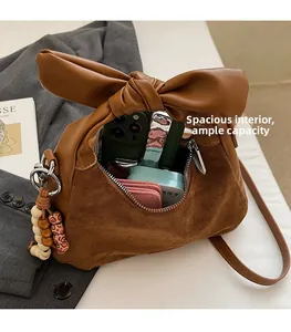 Détail d'un sac à main marron avec poignée à gros nœud et breloque en perles rétro