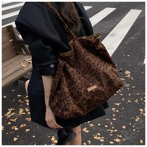 Street style view of oversized leopard print canvas tote bag on model in black suit