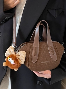 Secchiello marrone monogramma con charm peluche tenuto da modella in abito nero