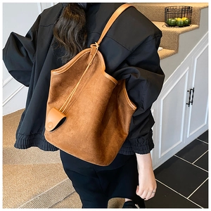 Detail view showing warm brown suede texture and leather strap of this large shoulder bucket bag