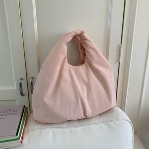 Dettaglio di una borsa tote imbottita rosa pallido con una texture soffice e morbida