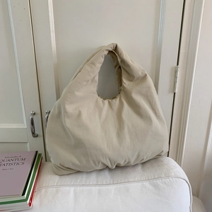 Dettaglio macro della borsa tote beige con texture morbida e manico dal design unico