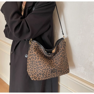 Detail of leopard print hobo bag with black leather trim and golden metal hardware
