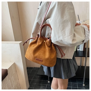 Close-up of matte suede bucket bag with leather drawstring and embossed fashion label