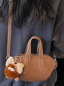 Borsa a secchiello minimalista in pelle marrone con trama e simpatico ciondolo a mostro