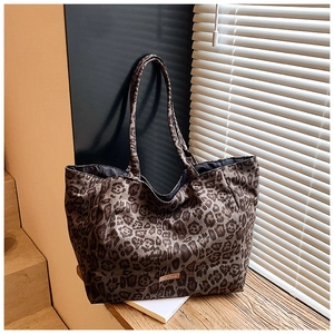 Close-up of leopard print canvas tote bag with slim shoulder strap and metal logo detail
