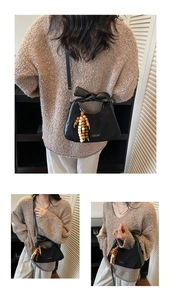 Détail du sac bandoulière noir avec un grand nœud et un pendentif en perles