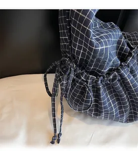 Detail view of navy blue checkered canvas bag showing drawstring closure and strap texture