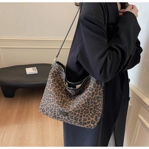 Detail of leopard print canvas bucket bag with black leather trim and metal logo plate