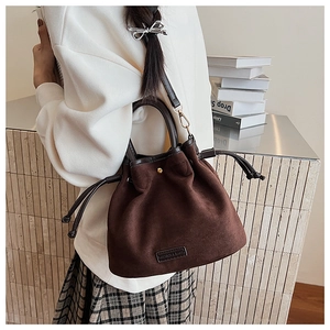 Detail of dark brown suede bucket bag with drawstring closure and logo tag