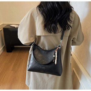 Detail of black Hobo bag with beaded charm and matte texture shown on a model back