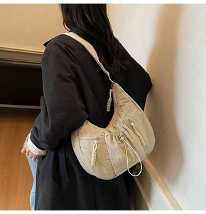 Detailed view of the beige nylon crescent bag with adjustable drawstring and woven zippers